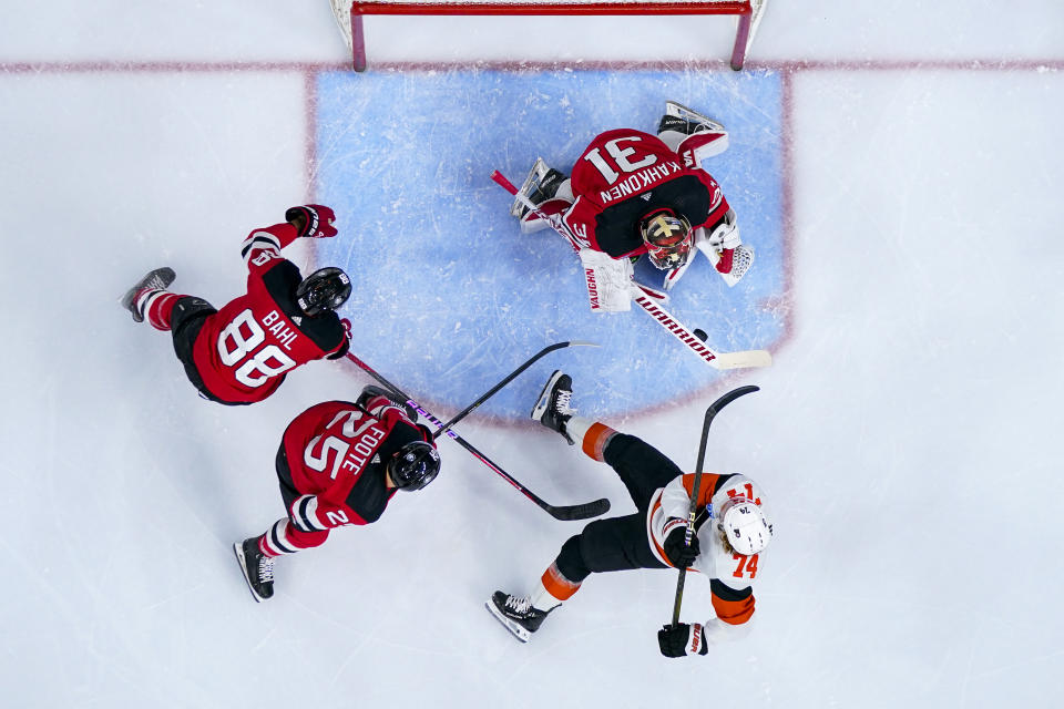 New Jersey Devils goaltender Kaapo Kahkonen (31) makes a save as Philadelphia Flyers' Owen Tippett (74) falls past Devils' Kevin Bahl (88) and Nolan Foote (25) during the second period of an NHL hockey game, Saturday, April 13, 2024, in Philadelphia. (AP Photo/Derik Hamilton)