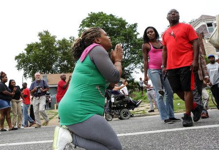 A woman prays in the street as police advance on Page Ave. to try to disperse a crowd that gathered after a shooting incident in St. Louis, Missouri August 19, 2015. REUTERS/Lawrence Bryant