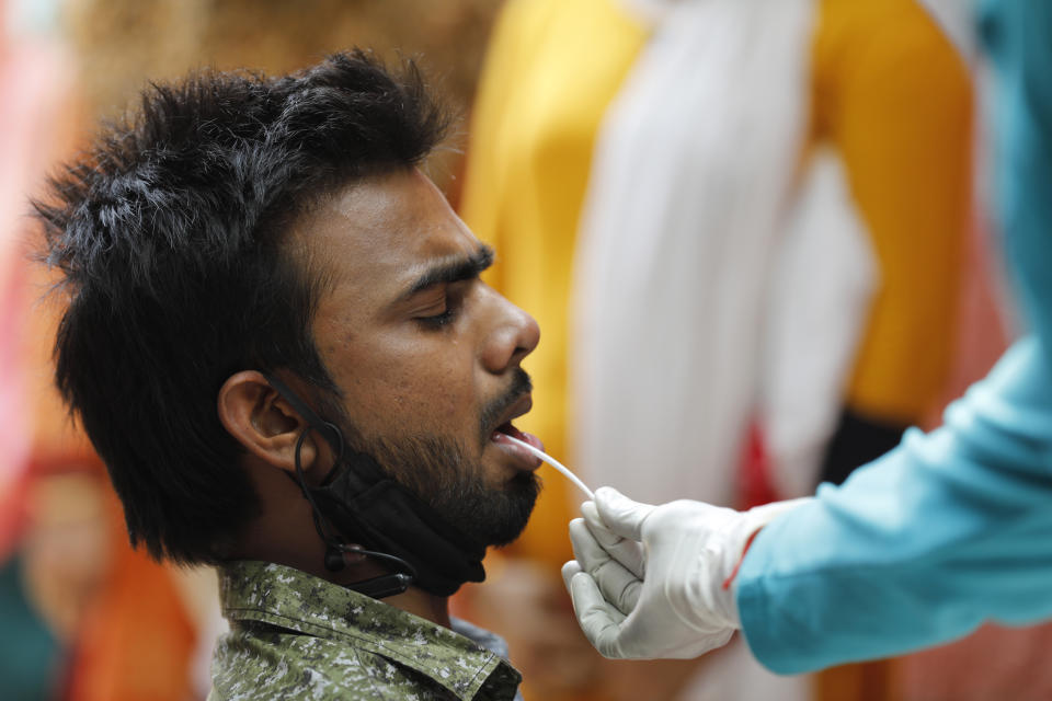 A health worker takes a swab sample to test for COVID-19 in Prayagraj, India, Saturday, April 17, 2021. The global death toll from the coronavirus topped a staggering 3 million people Saturday amid repeated setbacks in the worldwide vaccination campaign and a deepening crisis in places such as Brazil, India and France. (AP Photo/Rajesh Kumar Singh)