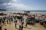 FILE - In this Thursday, June 6, 2019 file photo, people walk among vintage World War II vehicles parked on the beach during events to mark the 75th anniversary of D-Day in Arromanches, Normandy, France. In sharp contrast to the 75th anniversary of D-Day, this year's 76th will be one of the loneliest remembrances ever, as the coronavirus pandemic is keeping nearly everyone from traveling. (AP Photo/Thibault Camus, File)