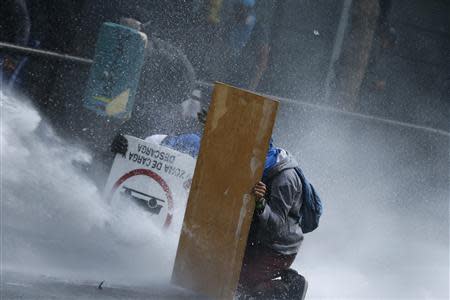 Anti-government protesters are hit by water from a water cannon during riots in Caracas April 20, 2014. REUTERS/Jorge Silva