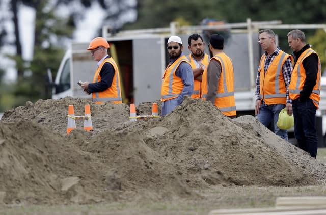 Members of New Zealand’s Muslim community and officials watch as graves are prepared at a Muslim cemetery