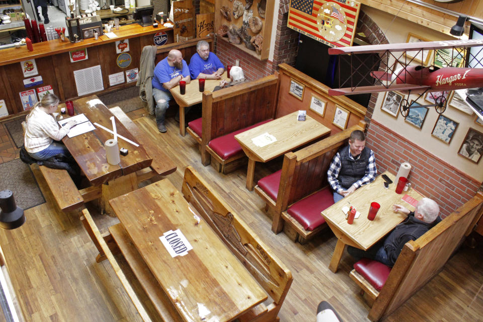 Diners sit at the Carver Hangar, a restaurant in Boring, Ore., on Jan. 6, 2021. As coronavirus deaths soar, a growing number of restaurants like Carver Hangar in states across the country are reopening in defiance of strict COVID-19 rules that have shut them down for indoor dining for weeks, or even months. (AP Photo/Gillian Flaccus)