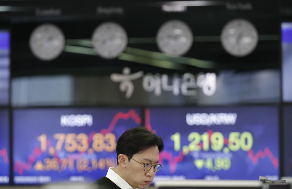 A currency trader watches the computer monitors near the screens showing the Korea Composite Stock Price Index (KOSPI), left, and the foreign exchange rate between U.S. dollar and South Korean won at the foreign exchange dealing room in Seoul, South Korea, Tuesday, March 31, 2020. Asian shares surged Tuesday after a rally in U.S. stocks, mostly spurred by health care companies' announcements of developments that could aid in the coronavirus outbreak. (AP Photo/Lee Jin-man)