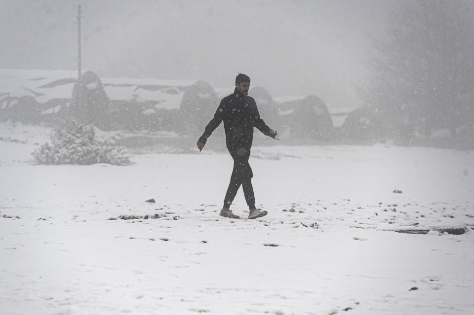 A migrant walks through snowfall at the Lipa camp, outside Bihac, Bosnia, Friday, Jan. 8, 2021. A fresh spate of snowy and very cold winter weather on has brought more misery for hundreds of migrants who have been stuck for days in a burnt out camp in northwest Bosnia waiting for heating and other facilities. (AP Photo/Kemal Softic)