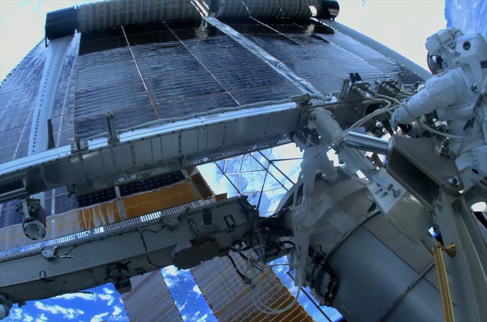 spacewalking nasa astronaut seen from the perspective of another astronaut outside the international space station, with earth in the background