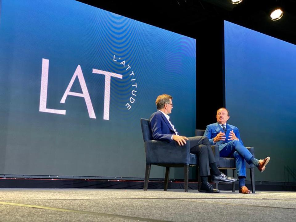 Two men talk while sitting in chairs.