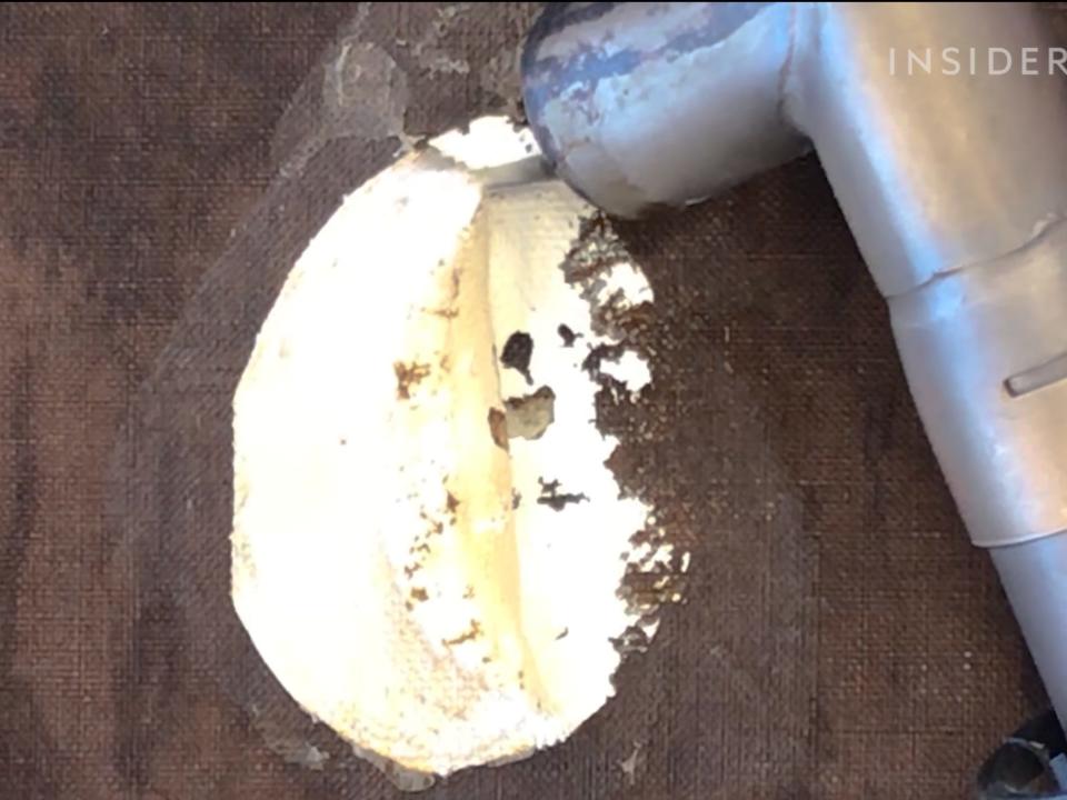 A heat gun removing paper from the back of a canvas