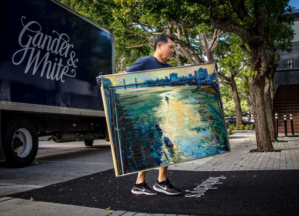 Oswaldo Perez, an art installer for Gander and White, carries Wayne Thiebaud's painting "River City (Sacramento River)," (1982) into the new Sotheby's Palm Beach location in January 2023.