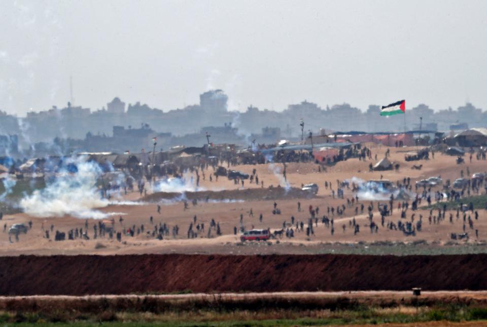 A picture taken on May 15, 2018 from the Israeli kibbutz of Mefalsim shows fumes from tear gas cannisters blowing amidst Palestinians protesting near the border east of the northern Gaza strip of Beit Hanun, during demonstrations marking the 70th anniversary of Nakba -- also known as Day of the Catastrophe in 1948 -- and against the US' relocation of its embassy from Tel Aviv to Jerusalem.&nbsp;