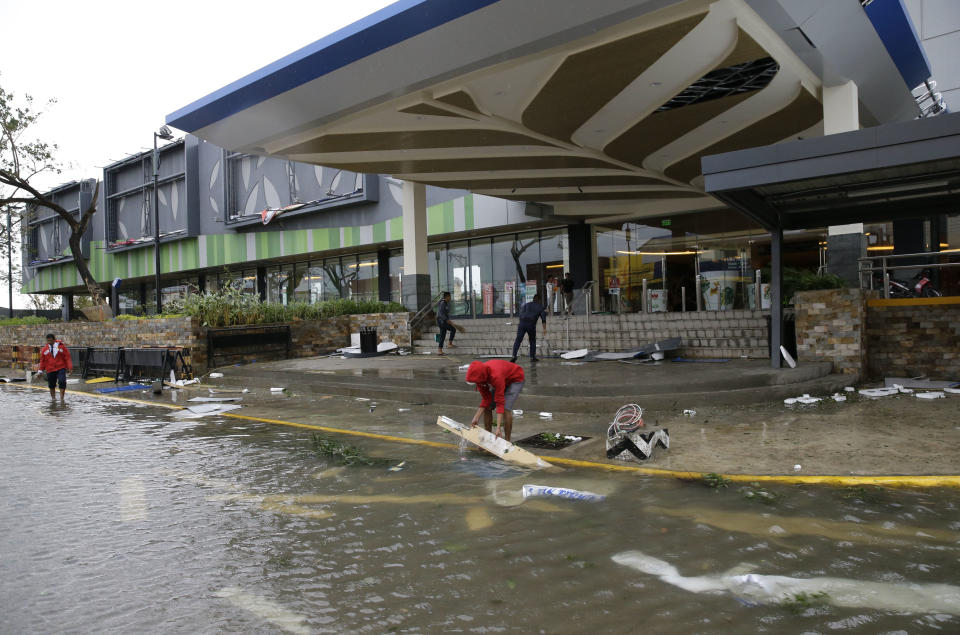 Workers clean up debris outside a mall that got partially damaged by strong winds from Typhoon Mangkhut as it barreled across Tuguegarao city in Cagayan province, northeastern Philippines on Saturday, Sept. 15, 2018. The typhoon slammed into the Philippines northeastern coast early Saturday, it's ferocious winds and blinding rain ripping off tin roof sheets and knocking out power, and plowed through the agricultural region at the start of the onslaught. (AP Photo/Aaron Favila)