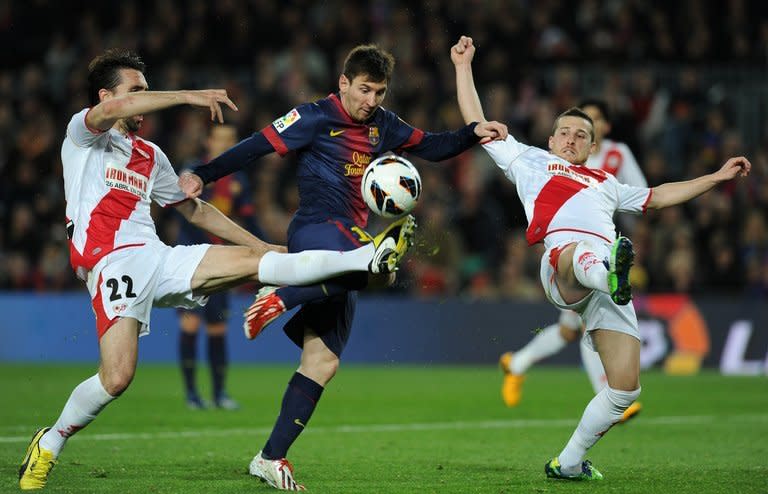 Barcelona forward Lionel Messi (C) is blocked by Rayo Vallecano's Jordi Figueras Montel (L) and Tito during their Spanish league match on March 17, 2013. Messi and teammate David Villa combined for all of Barca's goals in the 3-1 win over Rayo