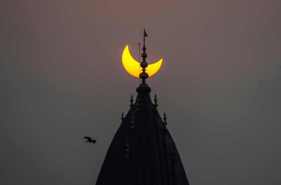 A partial solar eclipse is seen behind the centuries-old Raghunath Hindu temple in Srinagar, Indian controlled Kashmir, Tuesday, Oct. 25, 2022. 