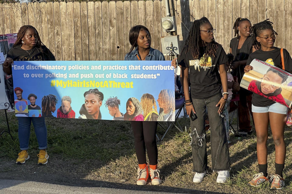 Supporters of Darryl George hold signs during a protest outside of the home of Barbers Hill Independent School District superintendent Greg Poole, Wednesday, Feb. 21, 2024 in Baytown, Texas. The group gathered in support ahead of a Thursday bench trial for Darryl George, a student who was punished over his hairstyle. George, who is Black and has been kept out of his regular classes since Aug. 31, 2023, says his hairstyle is protected by a new state law that prohibits race-based hair discrimination. (AP Photo/Juan Lozano)