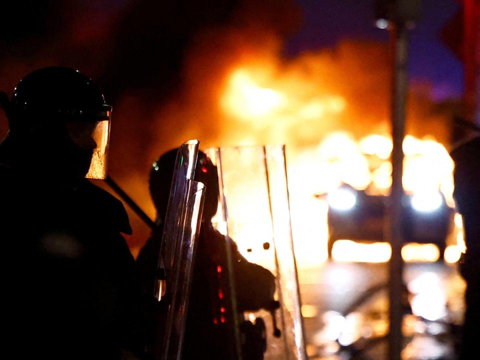 Riot police stand next to a burning police vehicle after riots broke out in Dublin (REUTERS)