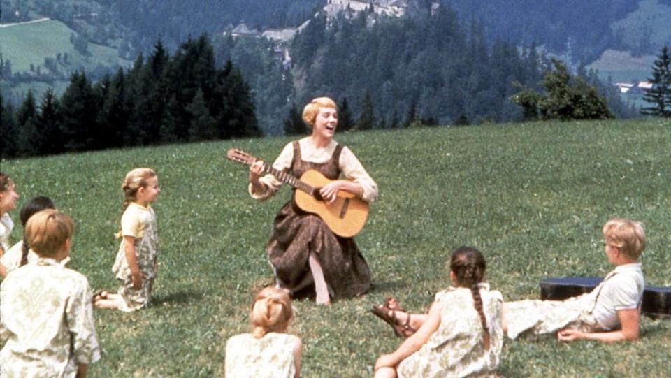 a woman sings in the grass surrounded by children
