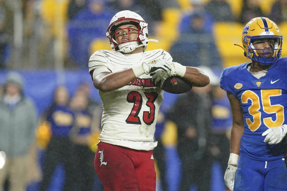 Louisville running back Isaac Guerendo (23) celebrates a touchdown next to Pittsburgh linebacker Braylan Lovelace (35) during the first half of an NCAA college football game in Pittsburgh, Saturday, Oct. 14, 2023. (AP Photo/Matt Freed)