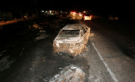 Motorists drive past the wreckage of cars burnt after a fireball from an tanker engulfed several vehicles and killed several people, near the Rift Valley town of Naivasha, west of Kenya's capital Nairobi, December 11, 2016. REUTERS/Thomas Mukoya