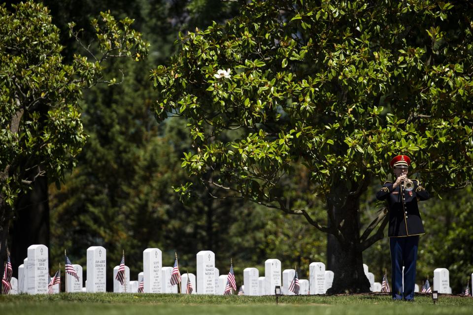 FILE - In this May 24, 2019 file photo, a U.S. Army Band bugler plays "Taps," during burial services for a North Carolina National Guard Sgt. at Arlington National Cemetery, in Arlington, Va. The Army is proposing new rules that would significantly restrict eligibility for burial at Arlington National Cemetery in an effort to preserve a dwindling number of gravesites well into the future. (AP Photo/Alex Brandon, File)