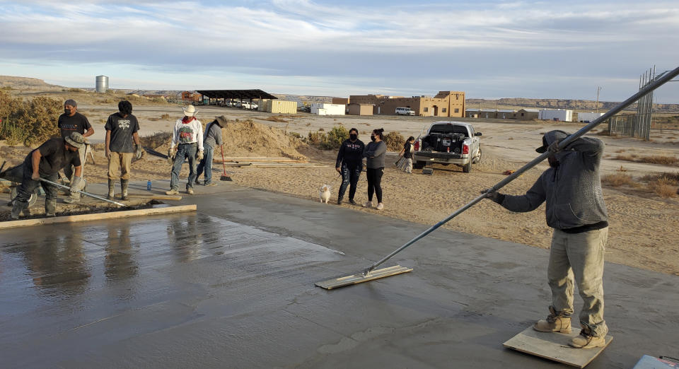 This undated photo provided by Brandon Nahsonhoya in August 2022 shows people working on a concrete pad for a skateboarding ramp in the Village of Tewa on the Hopi reservation in northeastern Arizona. A handful of Hopi youth worked together to create the skate spot that opened this spring. (Brandon Nahsonhoya via AP)