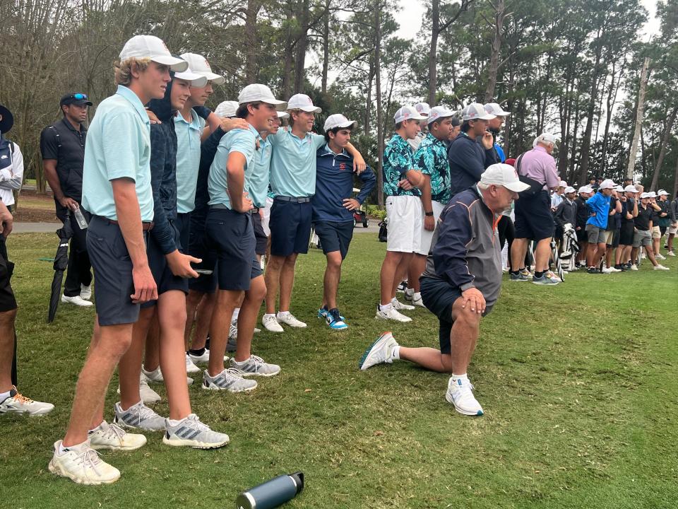 As the Bucs, and Tiger Woods at far left, await the final putt to see whether the 1A state championship will be theirs, Benjamin coach Toby Harbeck takes a knee Wednesday at Mission Inn Resort and Club in Howey-in-the-Hills.