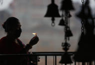 A Nepalese woman wearing face mask burns an oil lamp marking Biska Jatra festival during a lockdown to prevent the spread of the new coronavirus in Bhaktapur, Nepal, Monday, April 13, 2020. The festival that coincides with Nepalese New Year which is normally attended by thousands every year. (AP Photo/Niranjan Shrestha)