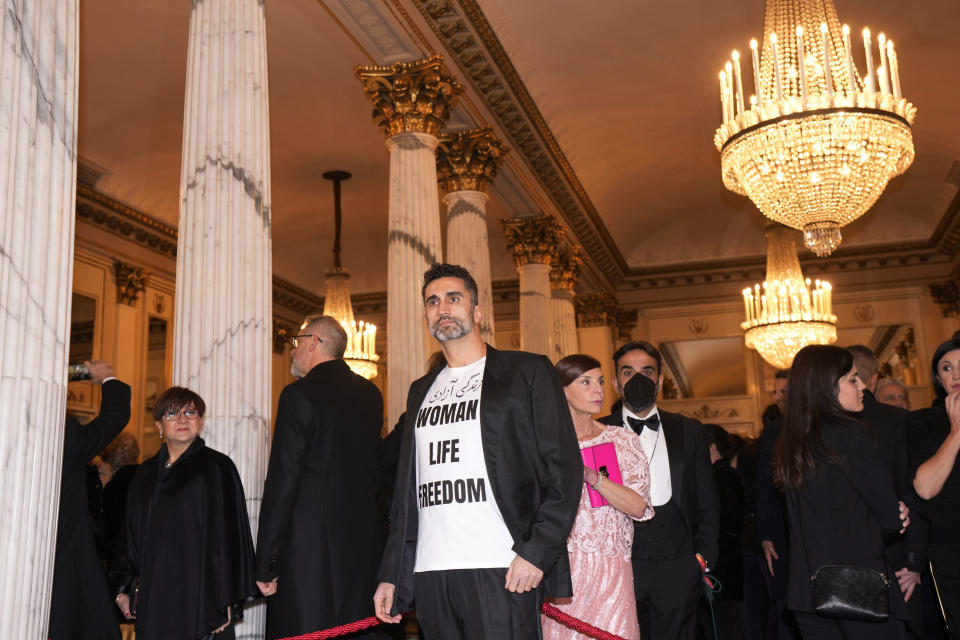 A man wearing a shirt reading "Woman Life Freedom" is seen before the premiere of Modest Mussorgsky's Boris Godunov in Milan, Italy, Wednesday, Dec. 7, 2022. Italy’s most famous opera house, Teatro alla Scala, opened its new season Wednesday with the Russian opera “Boris Godunov,” against the backdrop of Ukrainian protests that the cultural event is a propaganda win for the Kremlin during Russia’s invasion of Ukraine. (AP Photo/Antonio Calanni)