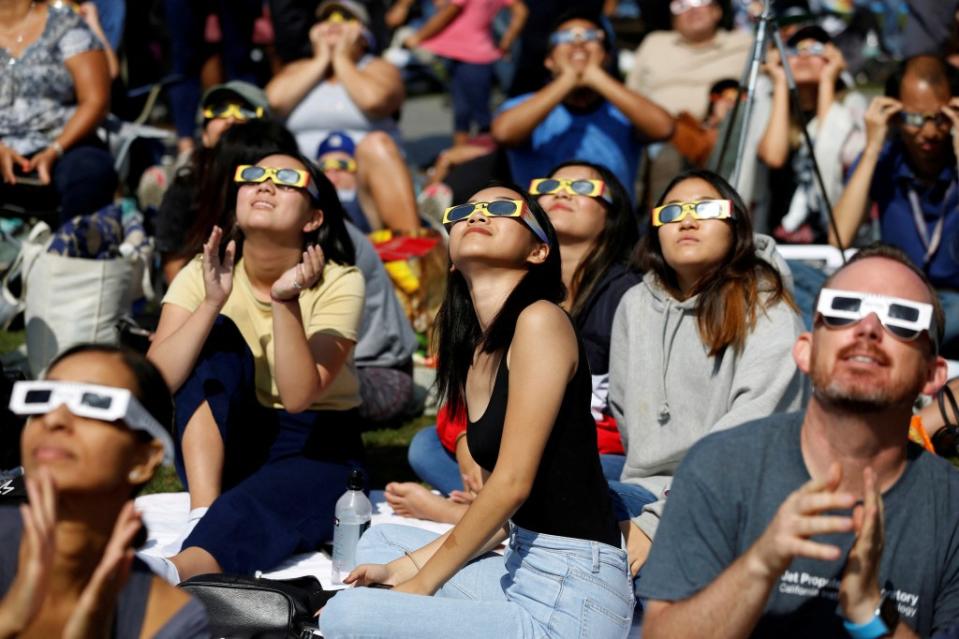 A group of people sitting on the lawn of Griffith Observatory in Los Angeles, watching the solar eclipse, dated August 21, 2017. REUTERS