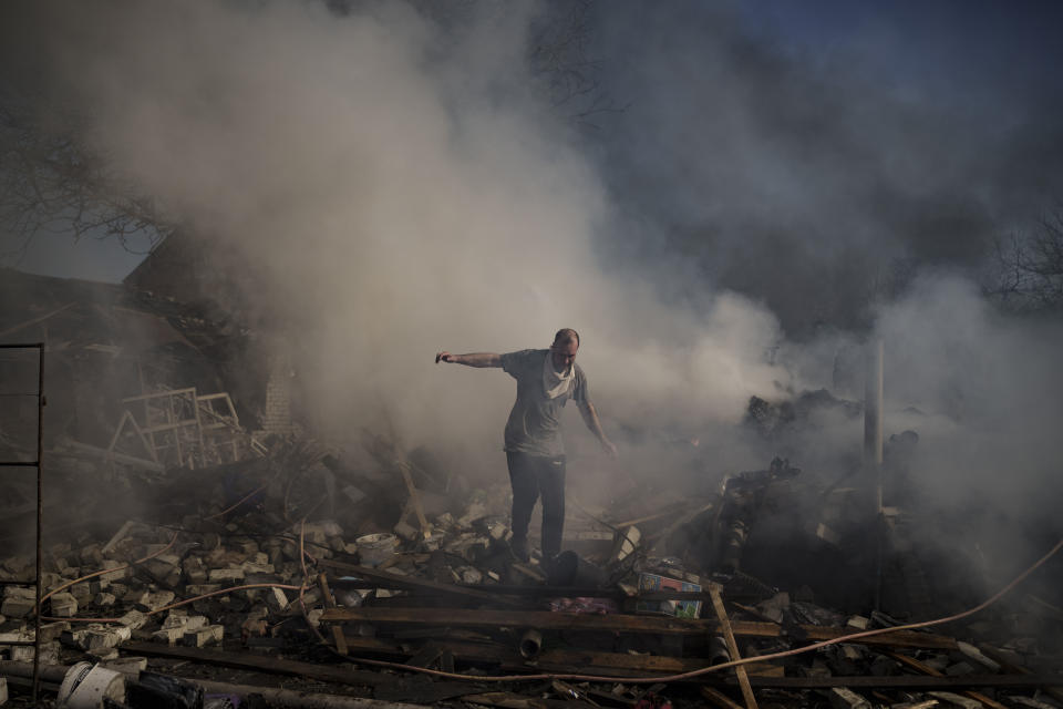 A man walks on the debris of a burning house, destroyed after a Russian attack in Kharkiv, Ukraine, Thursday, March 24, 2022