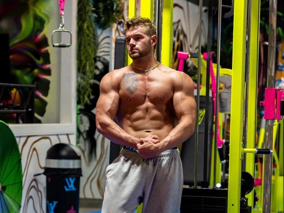 Muscled bodybuilder Ryan Schmidle poses in a gym.