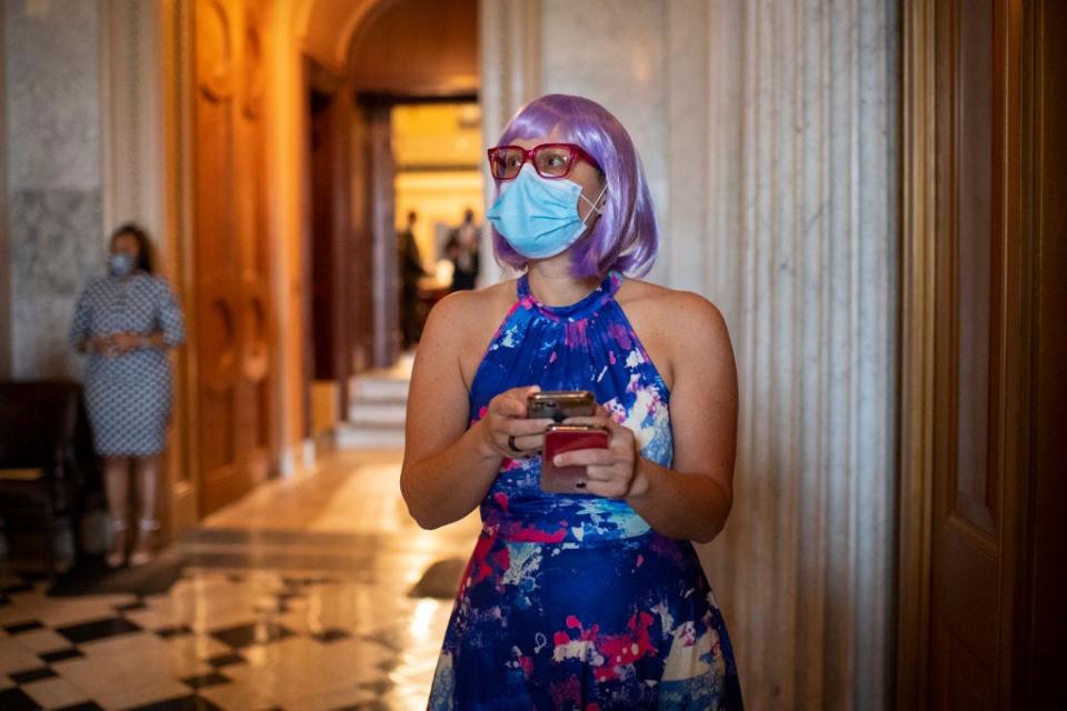 Kysten Sinema wears a purple wig and blue halter dress