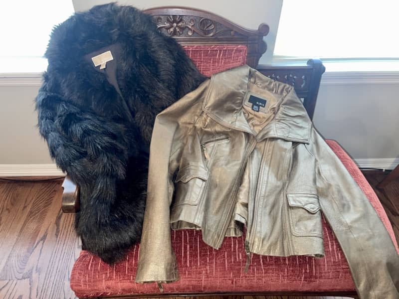 Fur and leather coats on fabric chair.