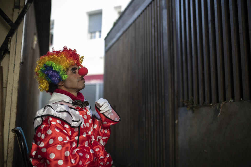 Belhussein Abdelsalam, a Charlie Chaplin impersonator puts on a clown outfit in a flower shop before performing, in Rabat, Morocco, Thursday, Dec. 31, 2020. When 58-year-old Moroccan Belhussein Abdelsalam was arrested and lost his job three decades ago, he saw Charlie Chaplin on television and in that moment decided upon a new career: impersonating the British actor and silent movie maker remembered for his Little Tramp character. (AP Photo/Mosa'ab Elshamy)