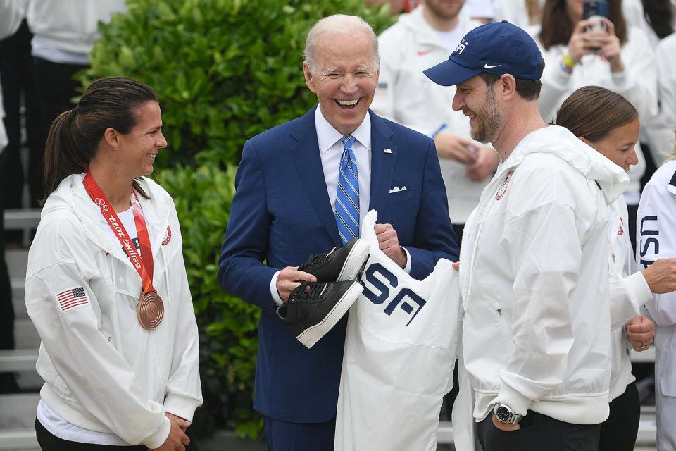 Olympic Speed Skater Brittany Bowe and Olympic Curler John Shuster present US President Joe Biden with a Team USA jersey during an event welcoming members of Team USA following their participation in the Tokyo 2020 Summer Olympic and Paralympic Games and Beijing 2022 Winter Olympic and Paralympic Games, during a ceremony on the South Lawn of the White House in Washington, DC, on May 4 2022