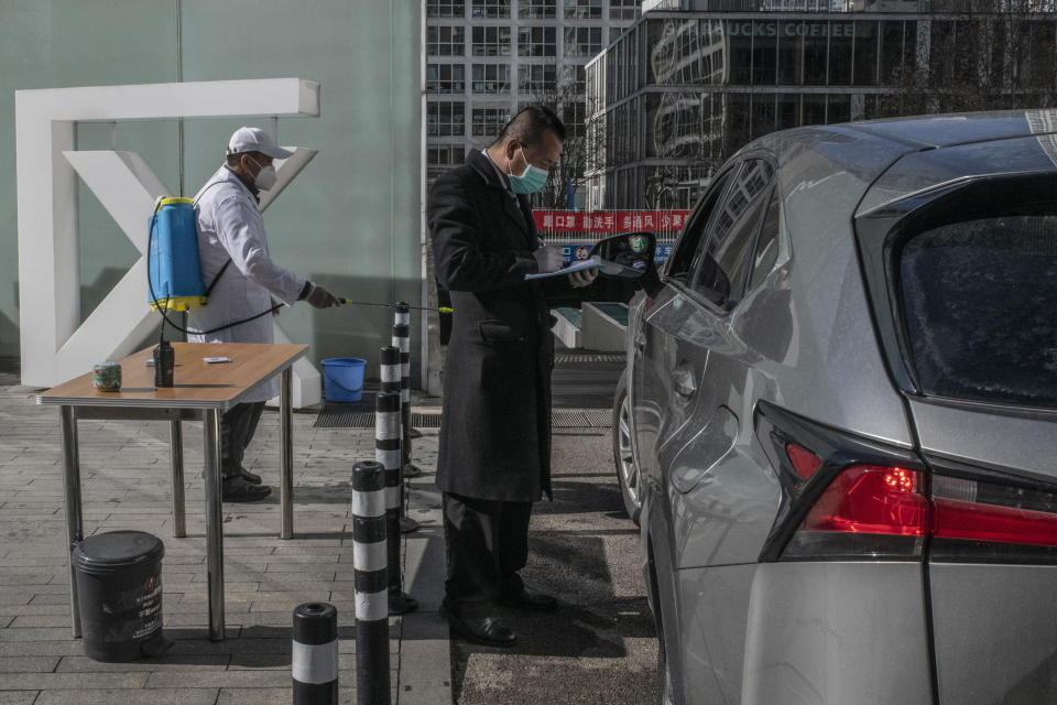 En la entrada del estacionamiento de un complejo de casas y oficinas en Pekín, registran a un conductor, le toman la temperatura corporal y rocían desinfectante en su auto, el martes 18 de febrero de 2020. (Gilles Sabrie/The New York Times)