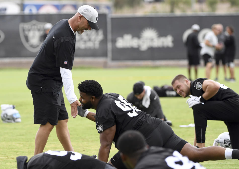 Las Vegas Raiders defensive coordinator Gus Bradley slaps the hand of defensive tackle Johnathan Hankins during an NFL football practice Friday, July 30, 2021, in Henderson, Nev. (AP Photo/David Becker)