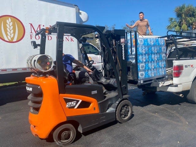 Karl Steidinger of the Midwest Food Banks of Florida helps move pallets of water to the back of a pick-up truck during Hurricane Ian relief efforts.