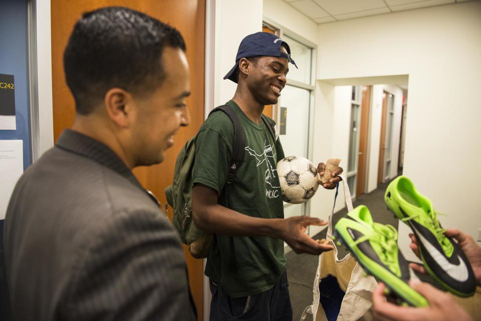 Attorney Cesar Vargas watches as his client Ivan Ruiz is given&nbsp;soccer shoes at the Safe Passage Project offices in Manhattan on Tuesday. (Photo: DAMON DAHLEN/HUFFPOST)