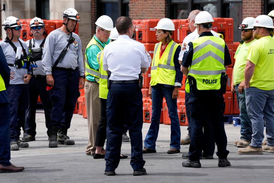 Iowa Gov. Kim Reynolds, center, talks with local officials while touring the site of an apartment building collapse, Monday, June 5, 2023, in Davenport, Iowa. The six-story, 80-unit building partially collapsed May 28. (AP Photo/Charlie Neibergall)