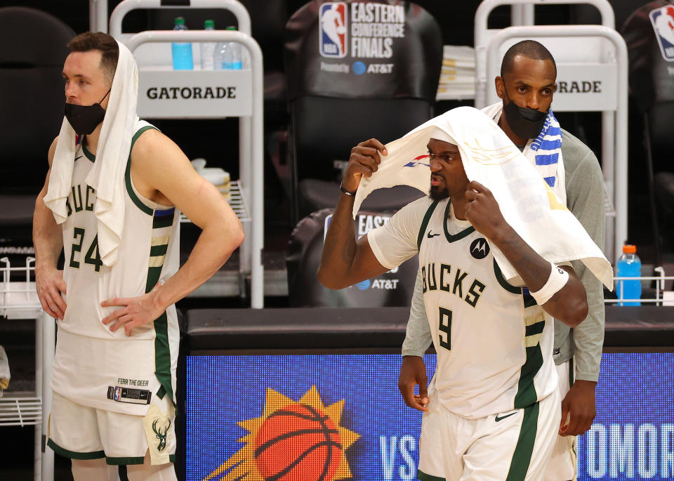 Bobby Portis puts a towel on his head and reacts to the Bucks' loss as his teammates look on dejectedly in the background.