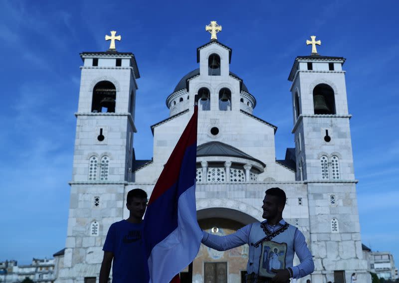 A supporter of pro-Serbian parties holds a Serbian flag and an icon in front of Serbian Orthodox Cathedral of the Resurrection of Christ, ahead of Montenegrin Assembly election in Podgorica