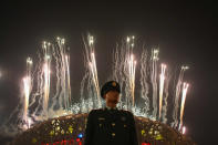 A Chinese policeman stands guard as fireworks explode over the National Stadium during the Closing Ceremony for the Beijing 2008 Olympic Games. (Photo by Andrew Wong/Getty Images)