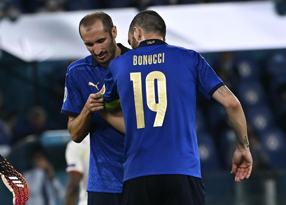 Italy's Giorgio Chiellini, left, gives the captain's armband to teammate Leonardo Bonucci before leaving the pitch during the Euro 2020 soccer championship group A match between Italy and Switzerland at Olympic stadium in Rome, Wednesday, June 16, 2021. (Andreas Solaro/Pool Photo via AP)