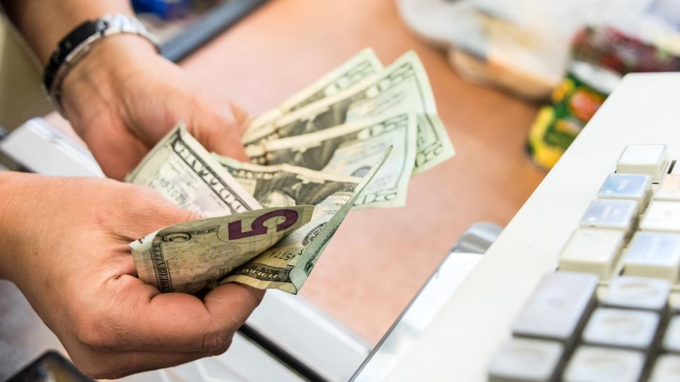 Convenient store female cashier counting the cash at the counter.