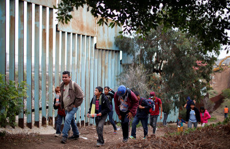 FILE PHOTO: Migrants from Honduras, part of a caravan of thousands from Central America trying to reach the United States, walk next to the border fence as they prepare to cross it illegally, in Tijuana, Mexico, December 14, 2018. REUTERS/Mohammed Salem/File Photo