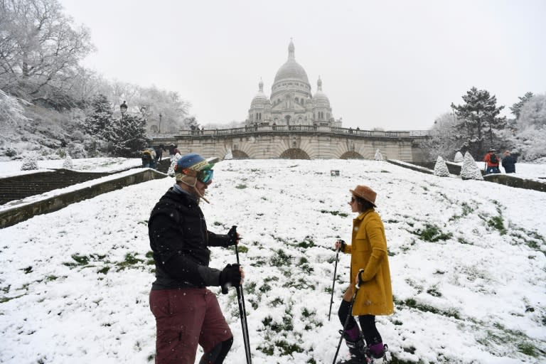 A couple prepare to ski on the snow-covered Montmartre hill in Paris