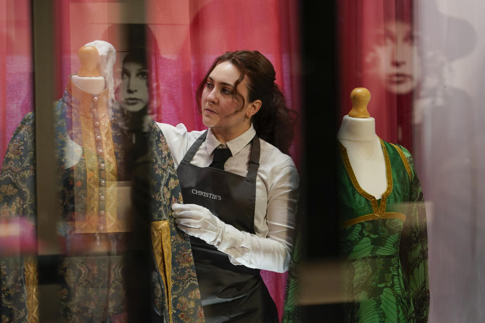 A member of staff poses next to dresses from The Pattie Boyd Collection, at Christie's, in London, Thursday, March 14, 2024. The dresses is estimated to sell within a range of £800-1,500. (AP Photo/Alberto Pezzali)