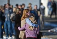 A woman puts her arm around a girl as students are reunited with their family members after being escorted out of Arapahoe High School, following a shooting incident where a student opened fire in the school in Centennial, Colorado December 13, 2013. The student seeking to confront one of his teachers opened fire at the Colorado high school on Friday, wounding at least two classmates before apparently taking his own life, law enforcement officials said. REUTERS/Evan Semon (UNITED STATES - Tags: EDUCATION CRIME LAW)