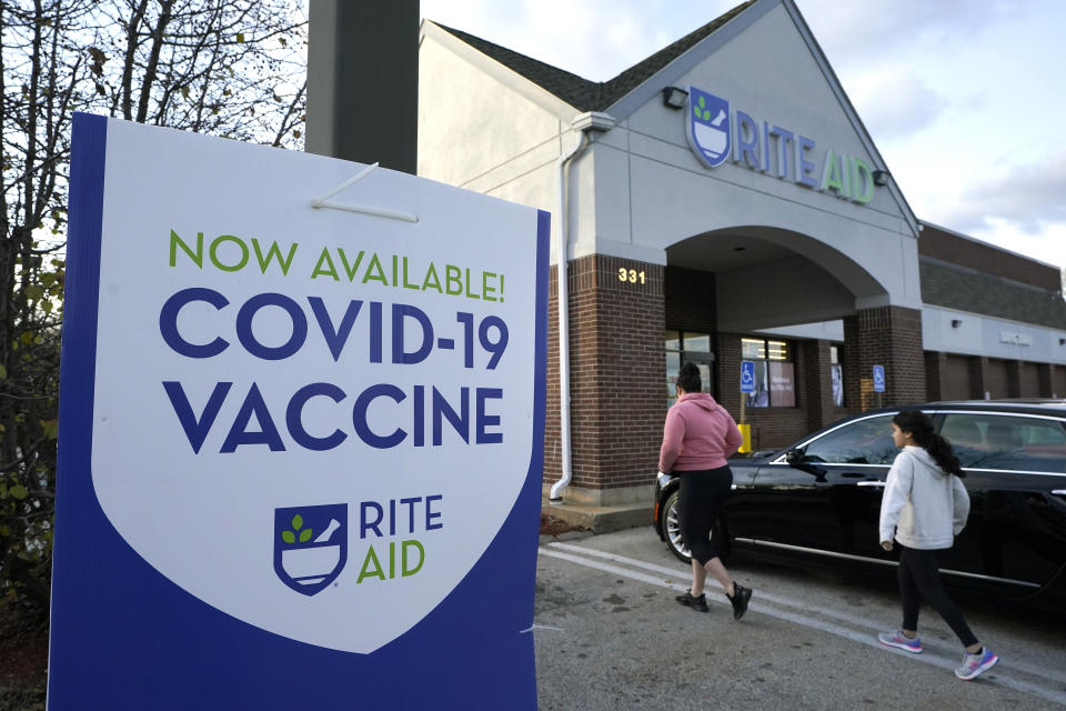 People walk past a COVID-19 vaccine sign as they enter a Rite Aid pharmacy, Tuesday, Dec. 7, 2021, in Nashua, N.H. Even as the U.S. reaches a COVID-19 milestone of roughly 200 million fully-vaccinated people, infections and hospitalizations are spiking, including in highly-vaccinated pockets of the country like New England. (AP Photo/Steven Senne)