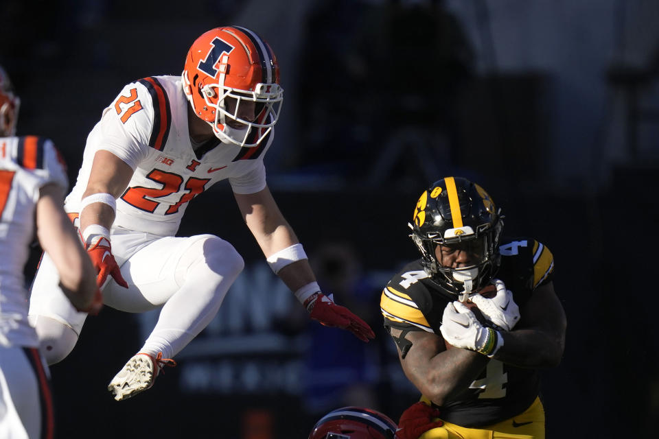 Iowa running back Leshon Williams (4) runs from Illinois defensive back Clayton Bush (21) during the first half of an NCAA college football game, Saturday, Nov. 18, 2023, in Iowa City, Iowa. (AP Photo/Charlie Neibergall)